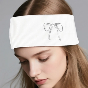 Close-up of white ribbed knit headband featuring a sparkling rhinestone bow detail