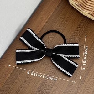 Dettaglio dell'elastico per capelli con fiocco nero e cuciture bianche, misura 11,5 cm