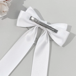 Barrette nœud en satin blanc avec chaîne argentée et pendentif L sur fond gris