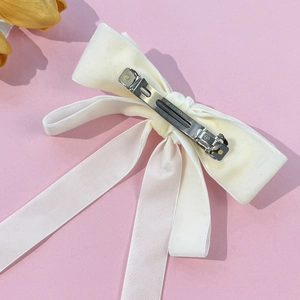 Elegant cream white velvet bow hair clip with long ribbons on pink textured background