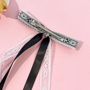 Lolita style lace bow hair clip with black and white ribbons on pink background