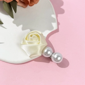 Détail d'une rose en satin et de perles sur une pince à cheveux en métal argenté