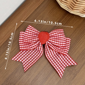 Detailed view of red and white plaid bow hair clip with a cute strawberry decoration