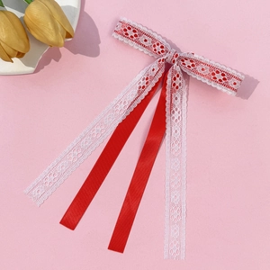 Detail view of handmade red satin and white lace bow hair clip with long flowing ribbons