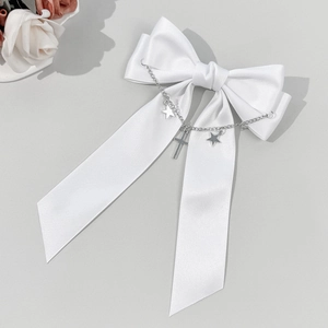 Détail du nœud en satin blanc avec des étoiles argentées, des chaînes et pendentif croix