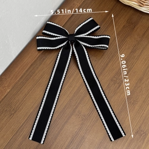 Elegante fiocco nero per capelli con cuciture bianche e lunghi nastri su legno