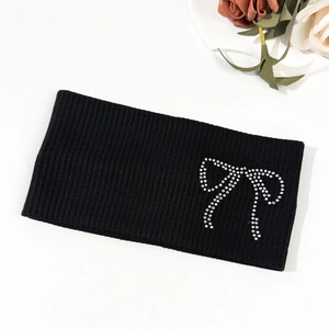 Close-up of black ribbed knit headband featuring a sparkling rhinestone bow detail