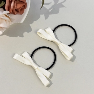 Détail de deux élastiques à cheveux avec nœuds en satin blanc crème et bandes élastiques noires
