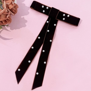 Macro shot of handmade dark brown velvet bow hairpin decorated with elegant white pearls