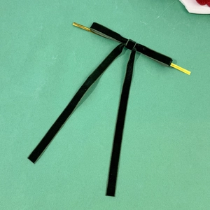 Detailed view of dark green velvet bow with gold twist ties for Christmas gift wrapping