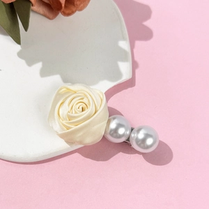 Détail d'une rose en tissu crème et de grandes perles blanches sur une barrette