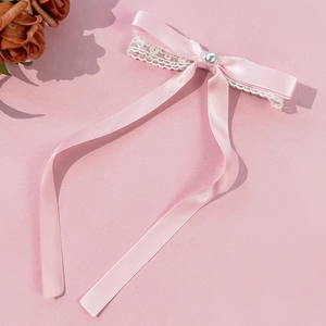 Pince à cheveux nœud rose avec dentelle et perle blanche sur fond rose pastel