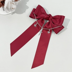 Détail de la barrette à nœud en satin bordeaux avec étoiles argentées et chaîne en croix