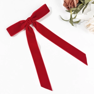 Detail of red velvet bow hair clip with long ribbons and elegant vintage silk texture