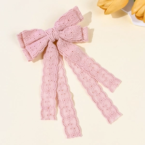 Detail of pink lace bow hair clip with intricate floral embroidery and long ribbons