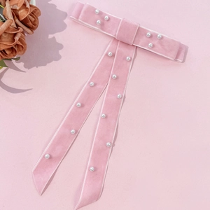 Detail of pink velvet bow hair clip with white pearl beads and elegant long ribbons