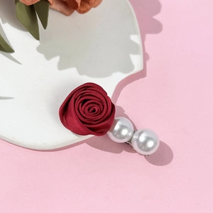 Détail de la pince à cheveux rose en satin rouge foncé avec deux perles sur base argentée