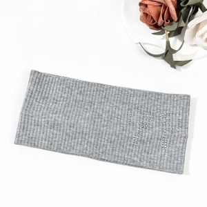 Detail of grey ribbed knit headband with sparkling rhinestone bow on white background