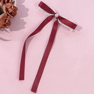 Détail de pince à cheveux avec nœud en satin bordeaux, dentelle blanche et perle