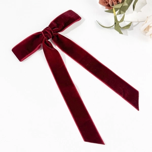 Detailed macro shot of elegant burgundy velvet bow hair clip with long ribbon streamers