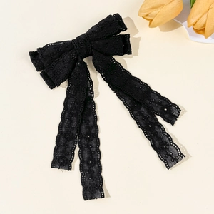 Detail of elegant black double-layered lace bow hair clip with long flowing ribbons