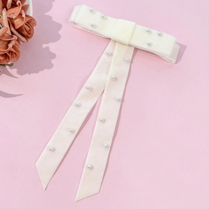 Close-up of cream velvet bow hair clip with delicate pearl beads and long elegant ribbons