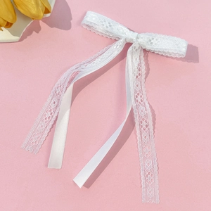 Detailed macro shot of white lace and silk ribbon texture on a bow hairclip