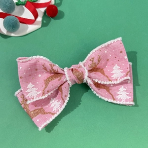 Dettaglio del fermaglio natalizio rosa con renna dorata e bordi in peluche bianco