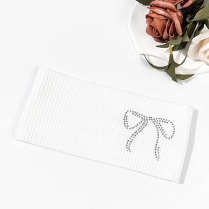 Close-up of white ribbed knit headband featuring a sparkling rhinestone bow detail