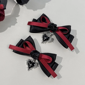 Detailed close-up of gothic hair clips with black ribbon bows and red rose pendants