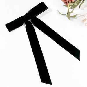 Detail shot of elegant long black velvet bow hair clip on a clean white background