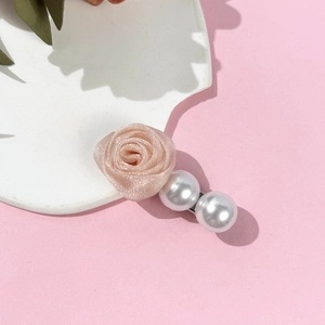 Vue détaillée d'une rose en tissu rose élégante et perles blanches sur pince à cheveux