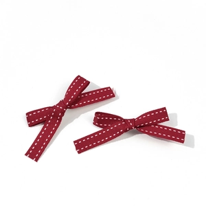 Dettaglio di fermagli per capelli a fiocco rosso con cuciture bianche e stile college
