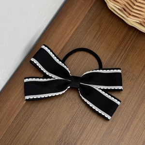 Dettaglio di un elastico per capelli a fiocco bianco e nero con cuciture a contrasto