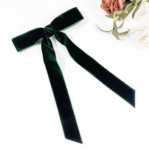 Detailed top view of a dark green velvet bow hair clip with elegant long streamers