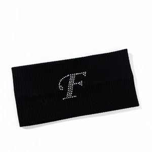 Detail of black knitted headband featuring a white rhinestone letter F decoration