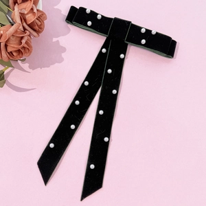 Detailed view of handmade black velvet bow hairclip with elegant faux pearl embellishments