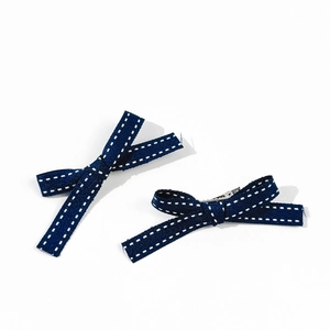 Dettaglio di fermagli per capelli a fiocco blu navy con nastro strutturato e clip metallica