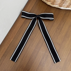 Dettaglio del fermaglio a fiocco bianco e nero con cuciture su una base di legno