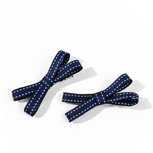 Dettaglio di fermagli per capelli a fiocco blu scuro con motivi bianchi e clip in metallo argento