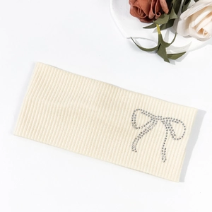 Detail of beige ribbed knit headband with sparkling rhinestone bow and soft texture