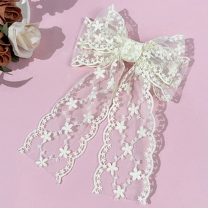 Elegant white lace bow hair clip with floral embroidery on a soft pink background