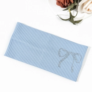 Detail shot of light blue ribbed knit headband featuring a sparkling rhinestone bow