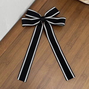 Dettaglio di fiocco in gros-grain nero con cuciture bianche a contrasto su legno