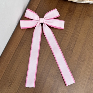 Dettaglio di un fiocco rosa per capelli con cuciture decorative su superficie in legno