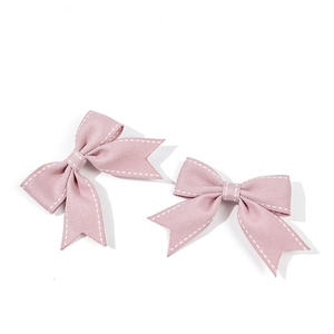 Dettaglio delle mollette per capelli a fiocco rosa con cuciture bianche e twill