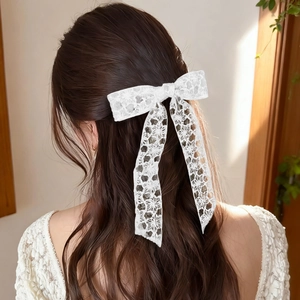 Elegant white lace bow hair clip with floral embroidery and long ribbons on model