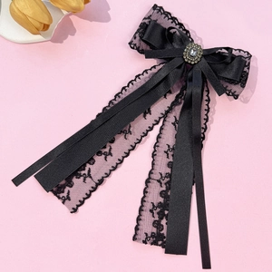 Detail of elegant black lace bow hair clip with central oval rhinestone and long ribbons