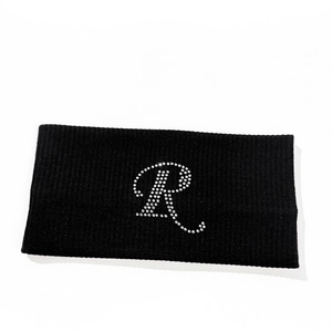 Detail of black ribbed knit headband featuring a sparkling rhinestone letter R design