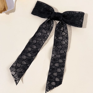 Detail of vintage black floral lace bow hair clip with long ribbons on light background